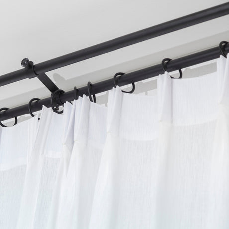 White shower curtain hooked on a black pole.