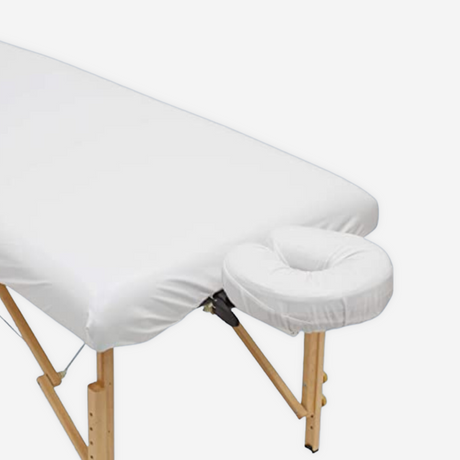 Spa massage table covered with white massage sheets. 