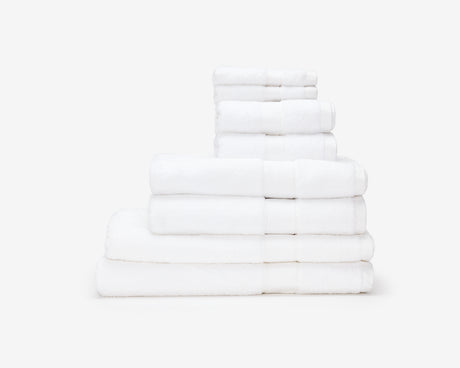 White hotel towels folded and placed on top of each other to form a pile.