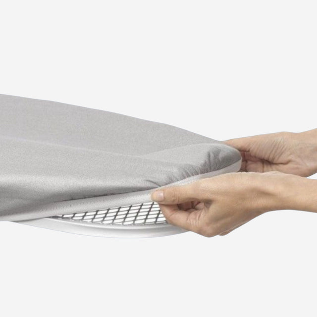 Grey ironing board cover being installed on an ironing board